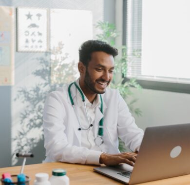 An Asian doctor uses a laptop to conduct an online consultation with a patient.