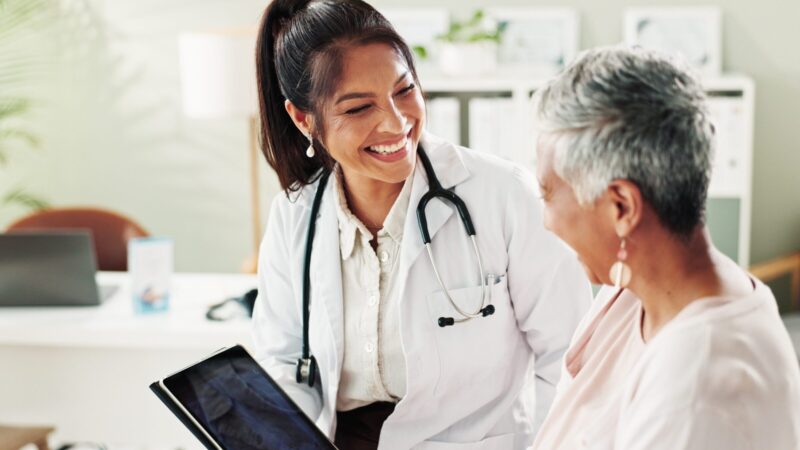 Mature woman, doctor and tablet for healthcare, support or conversation with checkup appointment in.