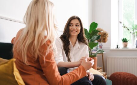 Mother and adult beautiful daughter having fun enjoying talk sit on sofa in modern living room at home