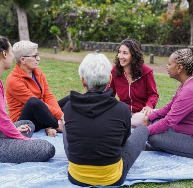 Multiracial women sitting and talking at city park - Multi generational people having fun together