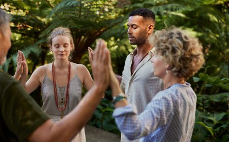 People in circle passing energy and praying together Group of diverse people stand in a circle holding hands, sharing a healing and spritual moment in nature. Multiethnic people at wellness retreat connect through energy practice in a lush outdoor setting. Adults meditate and praying together, creating a sense of unity and calm.