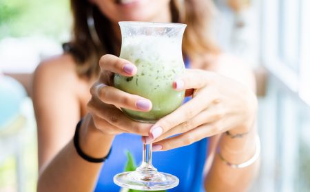 woman holds japanese matcha green tea with ice in glass in cafe woman holds japanese matcha green tea with ice in glass in cafe